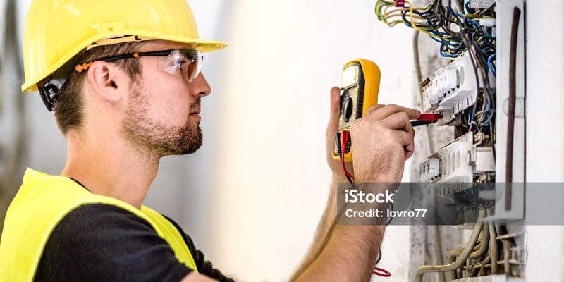 Electrician repairing circuit breakers in industrial electric panel.